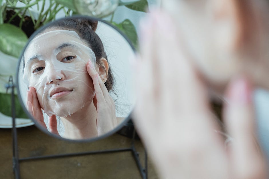 A woman in front of a mirror applying a sheet mask as part of her skincare routine