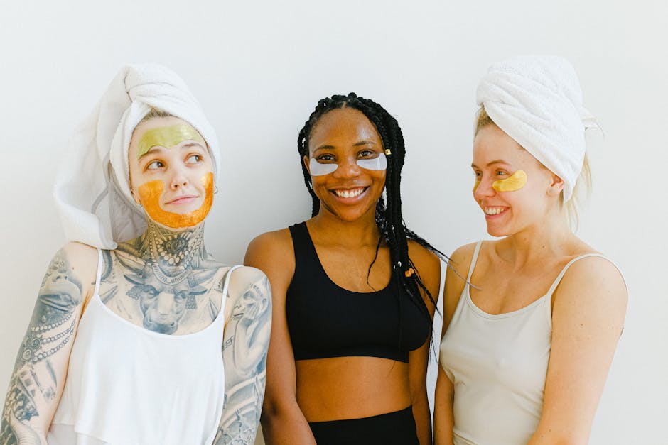 Three diverse women with face masks and towels smiling indoors, embracing wellness