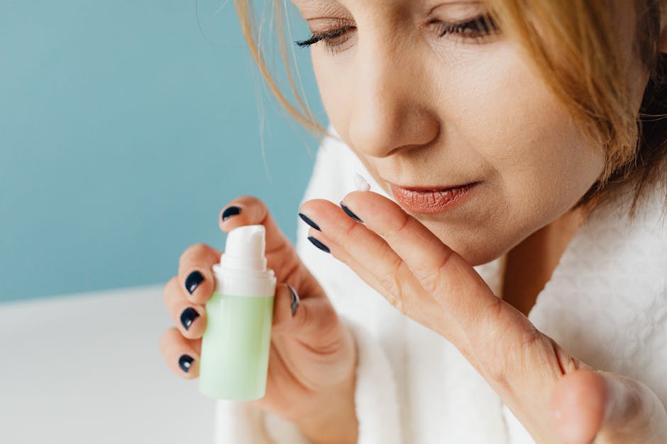 Close-up of a woman in a bathrobe applying skincare cream, focusing on self-care and beauty routine